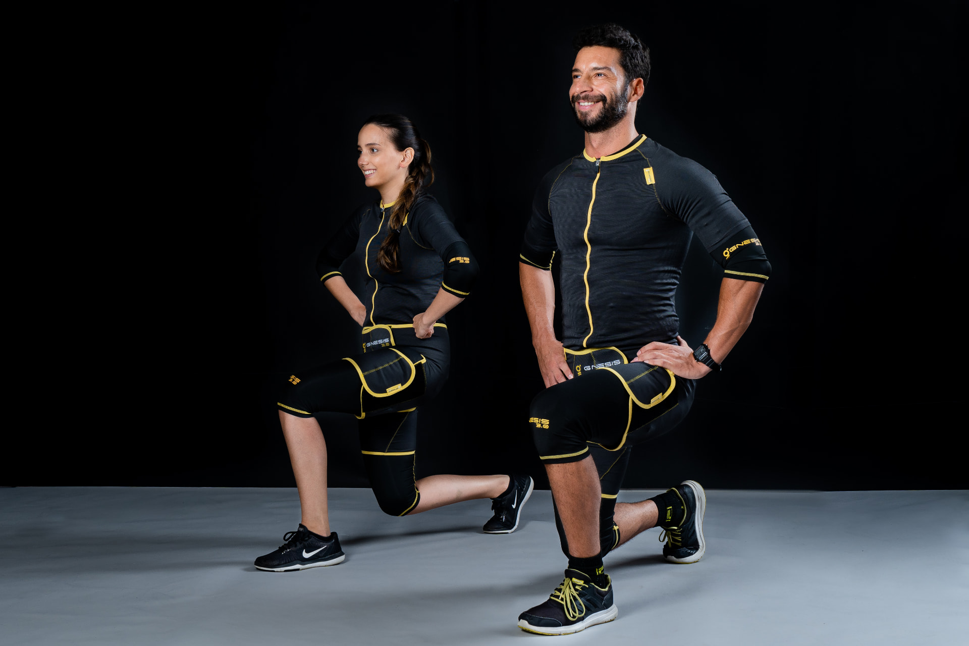 Two people wearing Gnesis EMS suits while lunging